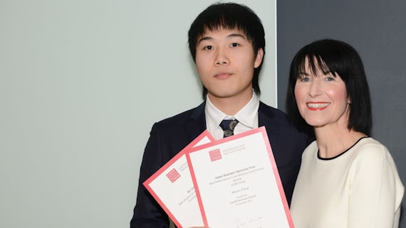 Male student collects two awards from Dean