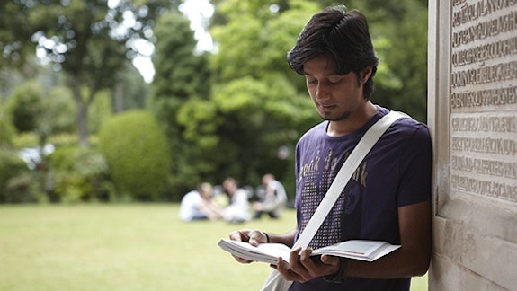Male student reading outside Main Building