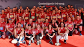 A large group of runners in red TeamCardiff shirts with Cardiff University logos on pose together