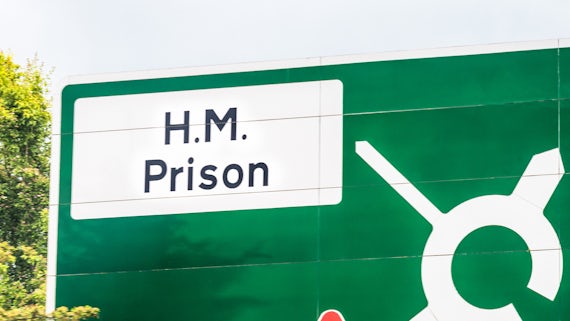 A UK road sign with directions to a prison