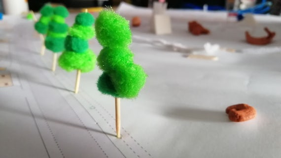 Artwork depicting trees, toothpicks with green fuzz on top to look like trees