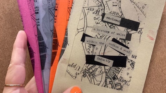 A woman holds a collection of zines in different colours