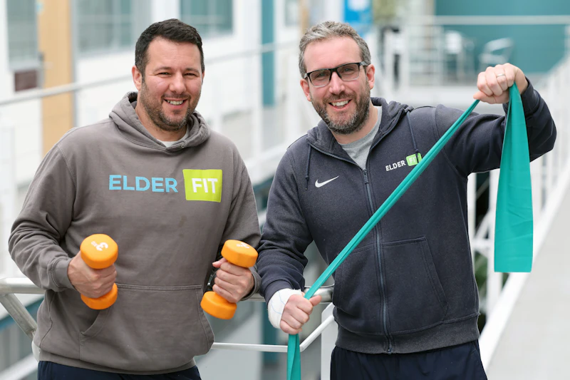 Two men who are fitness trainers stand and look at the camera inside Cardiff Medicentre