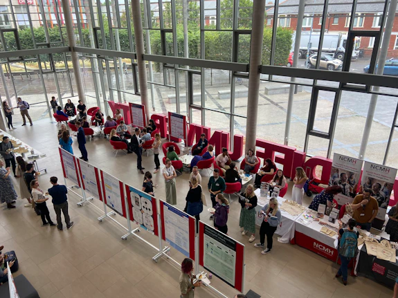 A photo from above of the Hadyn Ellis Building foyer showing lots of people talking and reading posterboards with scientific posters