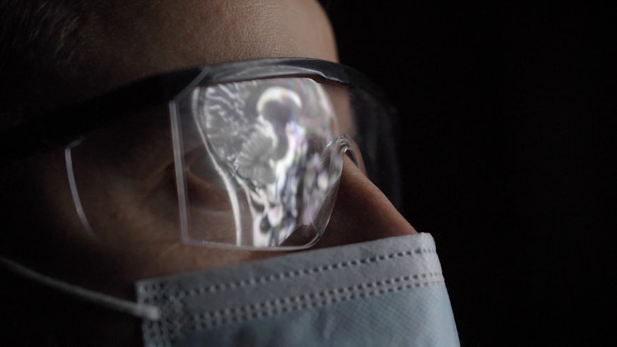 A radiologist looking at an MRI scan reflected in a medical visor.