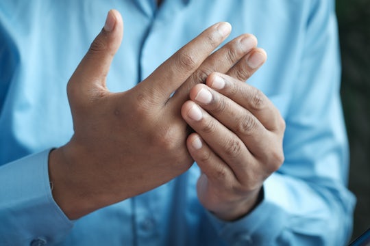 A man is rubbing the knuckles of his right hand.