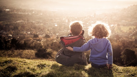 Two young children overlooking community from hillside