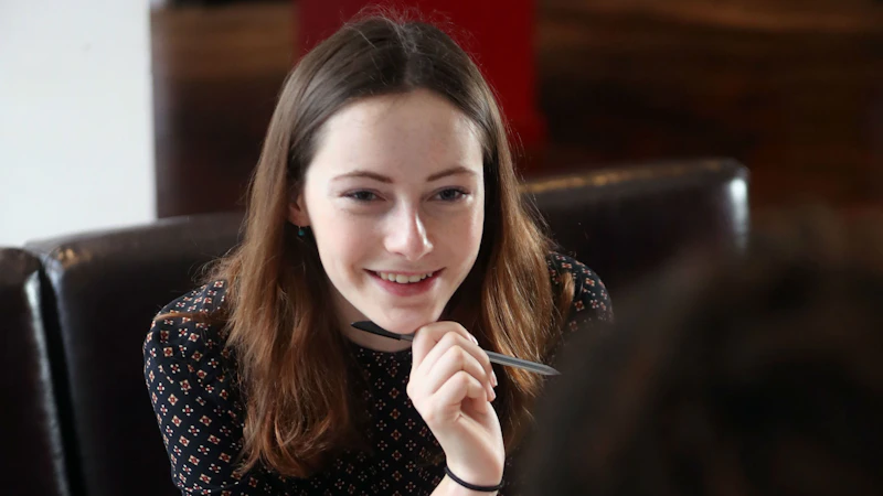 Student holding pen and smiling