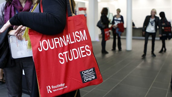 A woman holds a red bag with journalism studies written on it.
