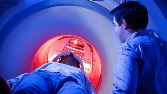 A researcher monitors a patient undergoing an MRI scan