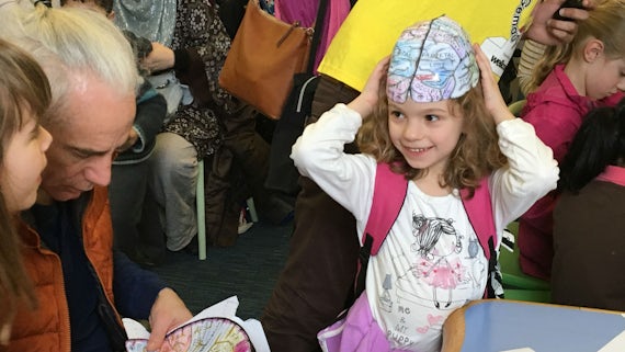 A little girl wears a makeshift brain on her head as part of brain games