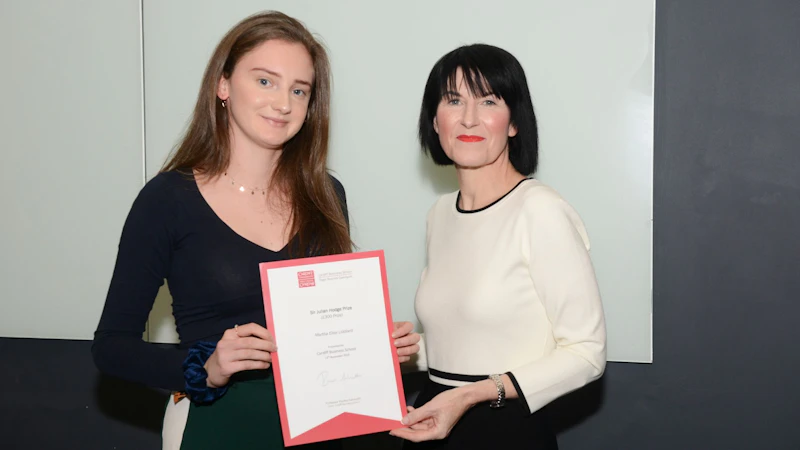 Female student collects award from Dean