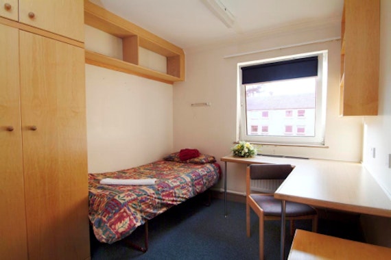 Bedroom with single bed, desk and chair and wardrobe.