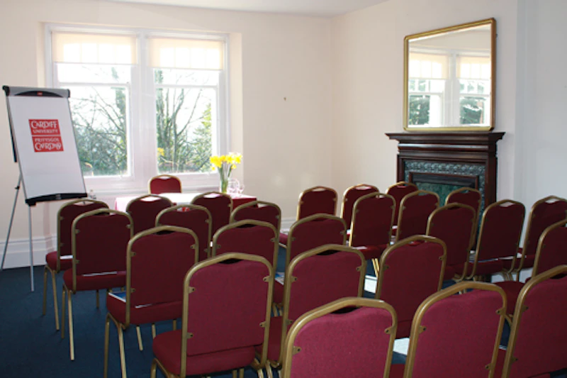 Room set out in theatre style, with chairs in rows and a table and flipchart at front.