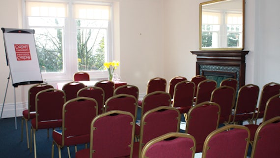 Room set out in theatre style, with chairs in rows and a table and flipchart at front.