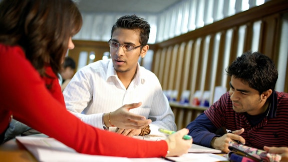 Three students around a table in a library