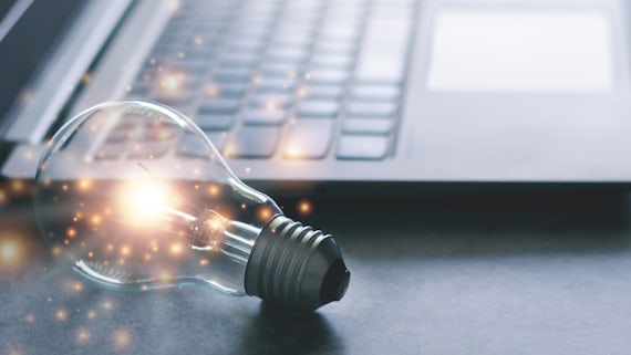 An image of a lightbulb next to a laptop