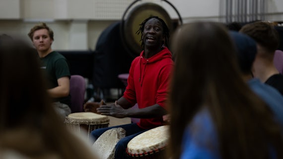 A number of students and staff members taking part in a drumming session