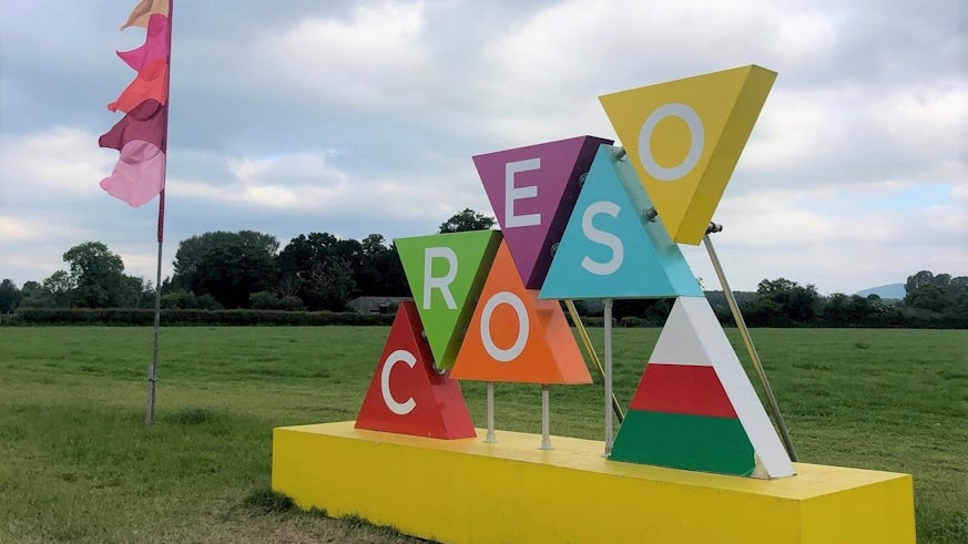 Multicoloured croeso sign in a field with trees in the background