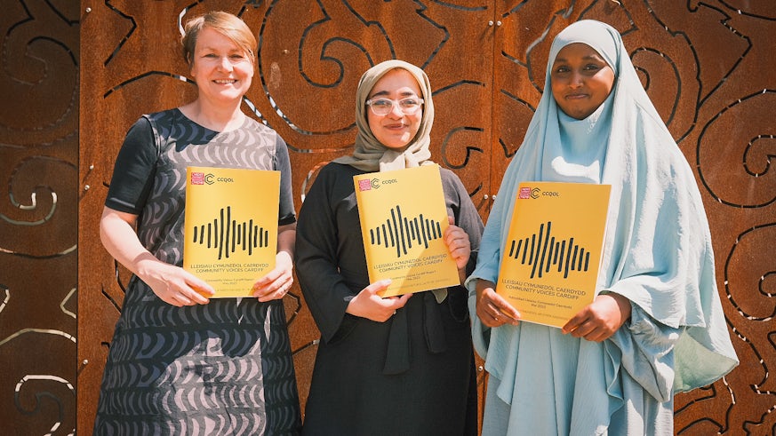 Three women holding copies of the Community Voices Cardiff report.