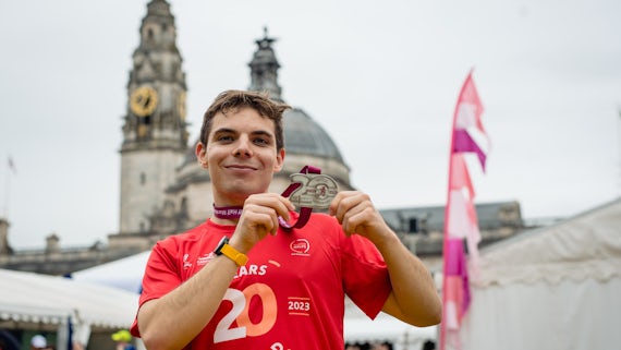 A man holds a medal after completing a half marathon