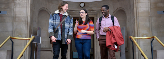 A group of three students have a discussion at the top of a staircase in the Glamorgan building.
