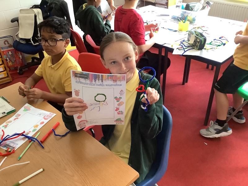 Schoolchildren show designs they have created using pipe cleaners.