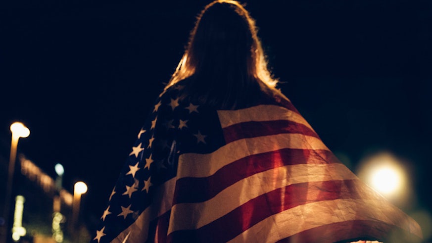 Woman draped in US flag at night