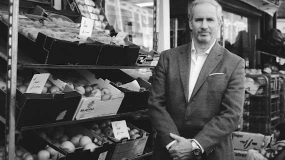 Rob Firth stands in front of a fruit stall 