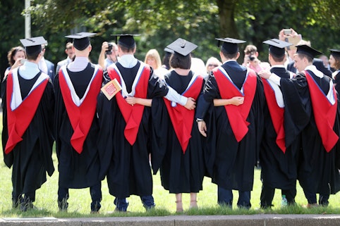 A line of Cardiff University graduates, one holding a Cardiff University flag