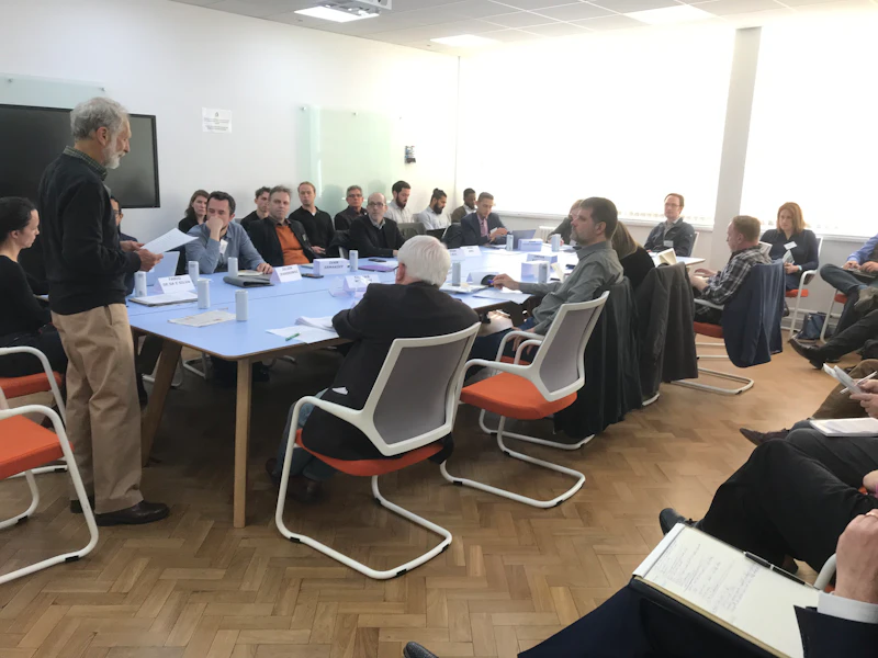 People around a table listening to someone speaking