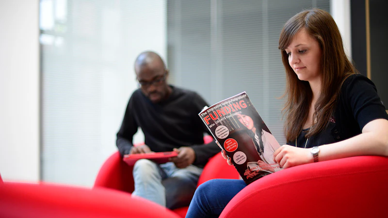 Female student sitting down, reading a magazine about funding