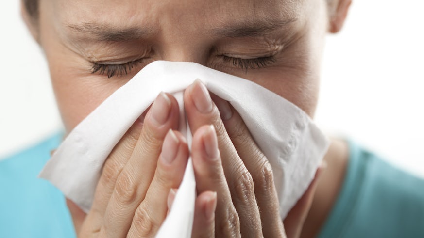 Lady sneezing into tissue 