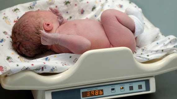 Stock image of newborn baby being weighed