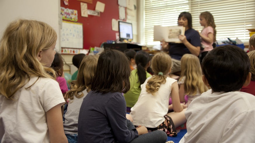 children on classroom floor listening to teacher