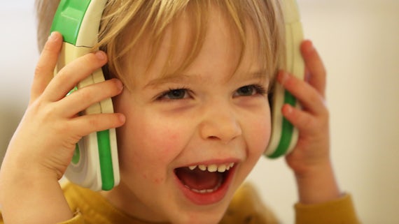 Boy smiling as he wears a pair of headphone
