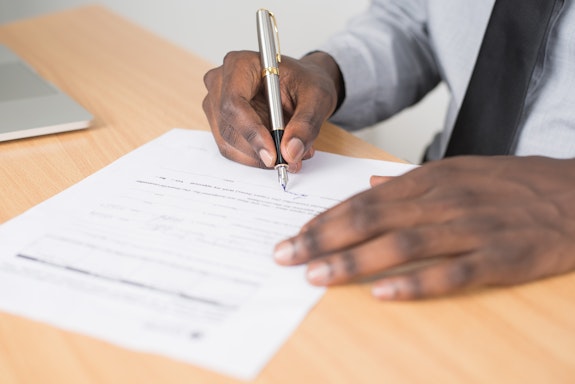 Black man holding pen fills in paperwork
