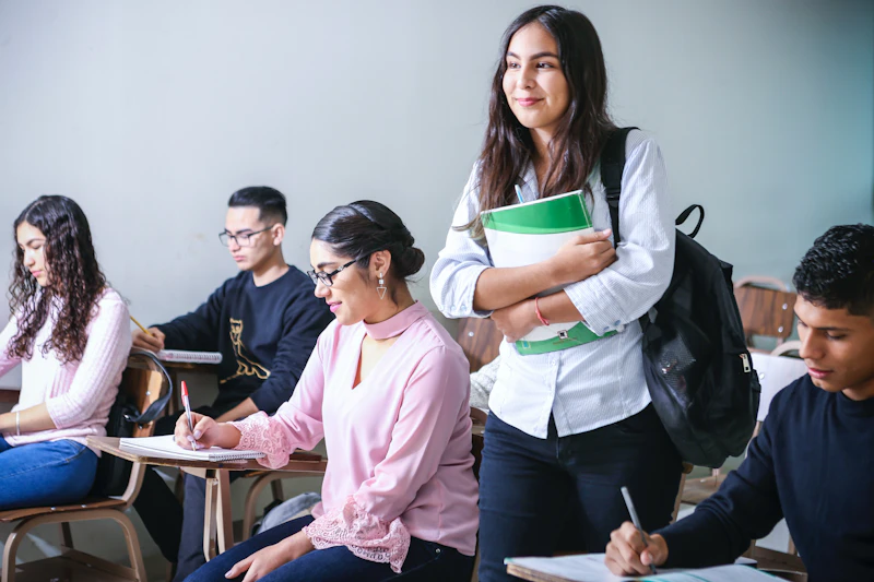 a young woman stands with folder in a classroom