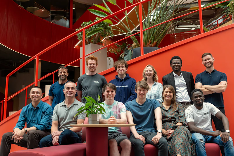 a group of people sitting on stairs inside a building look at the camera