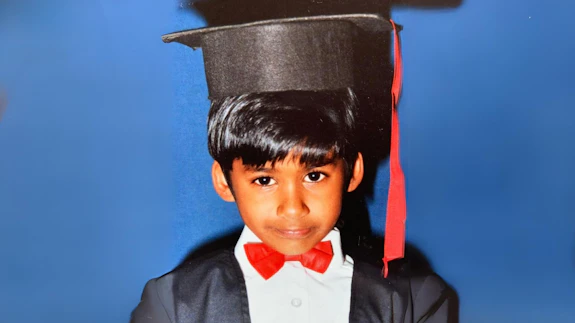 A child wearing a graduation gown