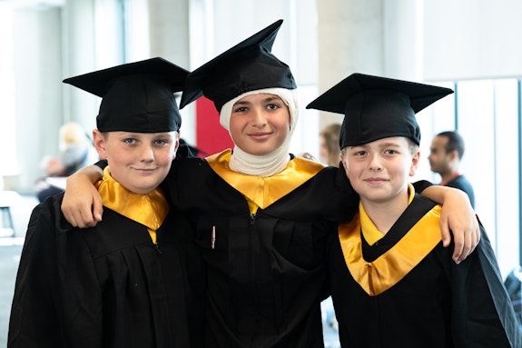 Three children wearing caps and gowns.