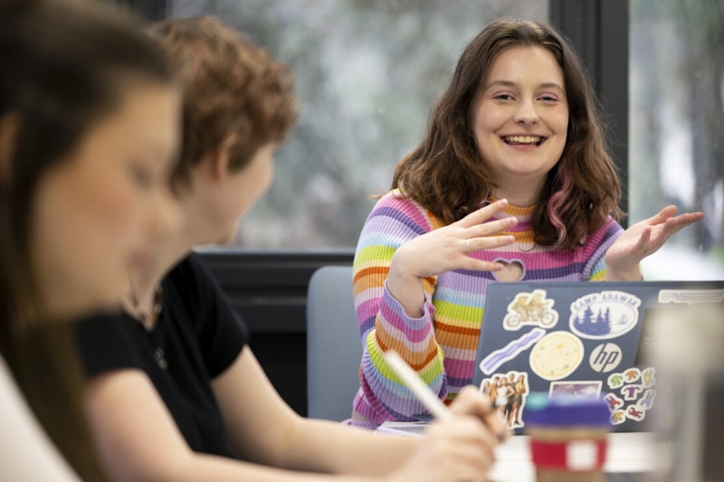 Group of sixth form students looking excited and happy as they read their exam results