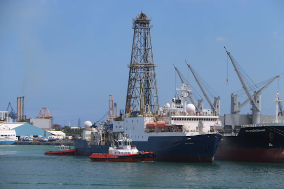 A drill ship is photographed docking in a port.