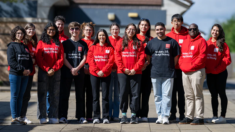 A group of people standing together, wearing red and black shirts with text on them.