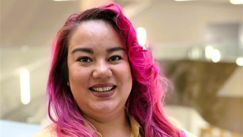 A young lady with pink hair is smiling at the camera.
