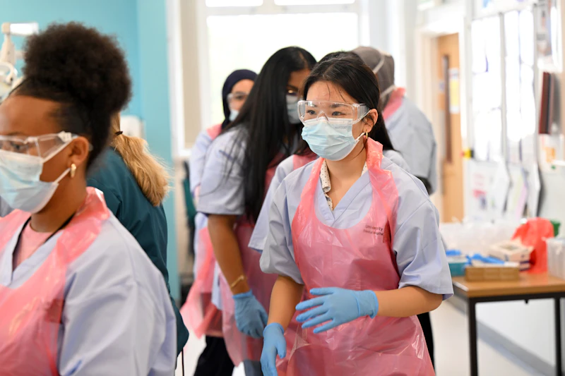 Participants wearing aprons and gloves taking part in a dentistry session at the Step Up summer school.
