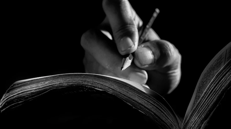 An image of a person holding a pencil and writing in a book