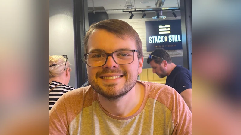 A man is smiling at the camera. He's wearing glasses.
