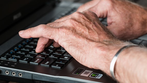 Photograph of a person's hands typing on a laptop