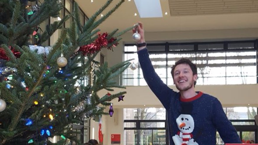 Image of student placing a bauble on the Christmas tree